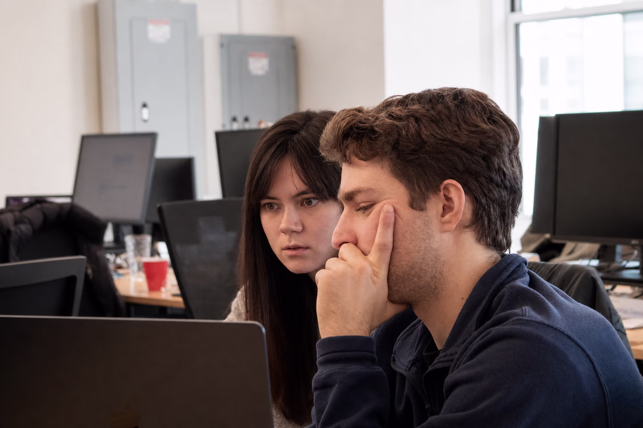 Two colleagues looking closely at a computer screen in the EliseAI office