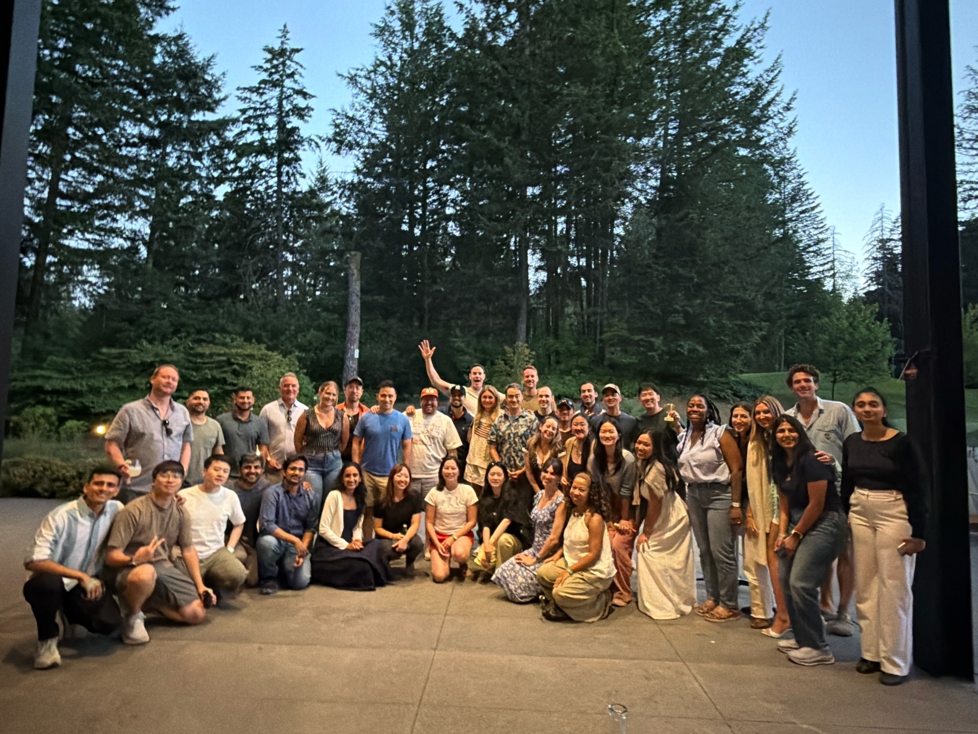 Raspberry AI team on a concrete pavilion, tall evergreens, golden hour.